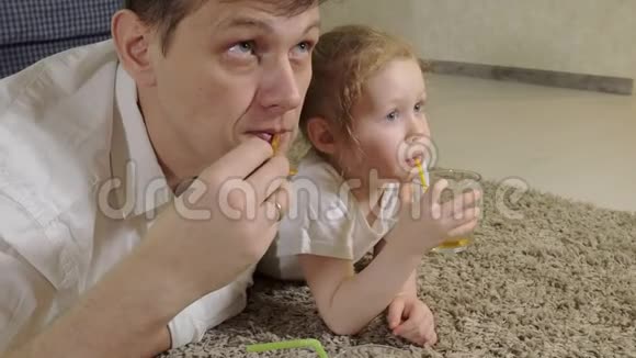 男人和女儿看电视坐在地上喝果汁视频的预览图