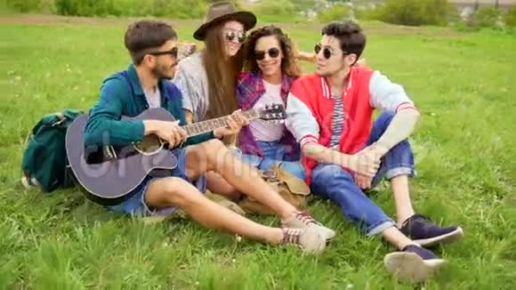 一群年轻英俊的人在野餐而他们弹吉他和唱歌夏季概念的朋友视频的预览图