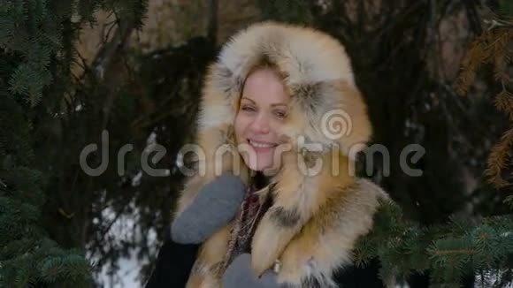 美丽的年轻模特参加冬天在树林里的照片拍摄她微笑地看着相机慢慢视频的预览图