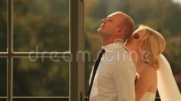 蜜月期间在阳台上拥抱美丽的新娘和英俊的新郎视频的预览图