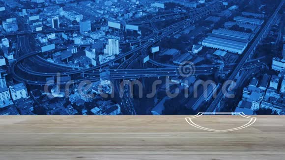 在木桌上悬挂盾牌平面图标的飞机俯瞰现代城市塔楼街道高速公路和摩天大楼商业视频的预览图