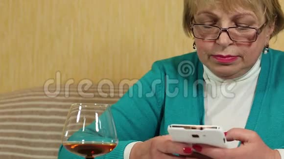 有白色智能手机的女人写短信喝白兰地视频的预览图