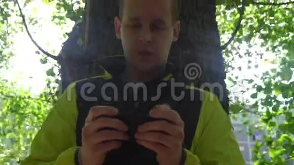 年轻人打电话在绿树的背景下视频的预览图