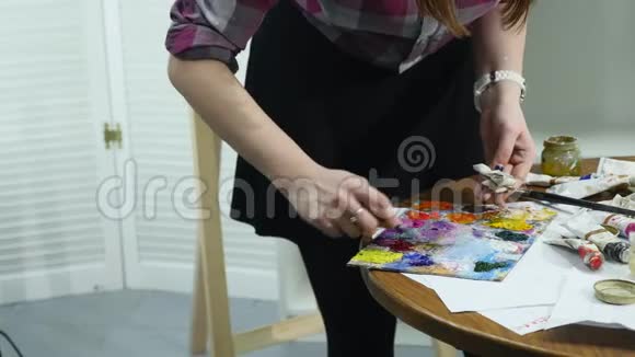 特写镜头的女性手挤出一管油漆到调色板上视频的预览图