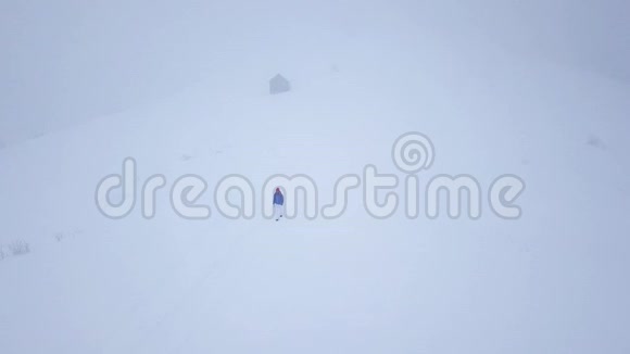 飞过一个孤独的旅游女孩她走在一座被雪覆盖的山顶上不舒服不友好视频的预览图