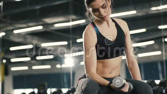 漂亮的年轻女孩在健身房背景下和哑巴一起做运动视频的预览图