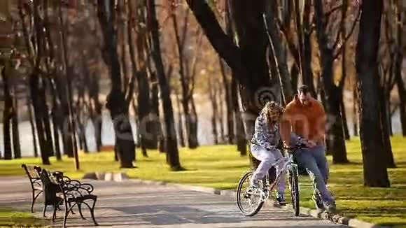 年轻而快乐的一对夫妇在公园里学骑自行车和飞艇视频的预览图