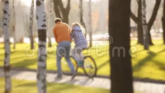 年轻而快乐的一对夫妇在公园里学骑自行车和飞艇视频的预览图