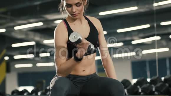活泼的女孩用哑铃做运动在健身房工作视频的预览图