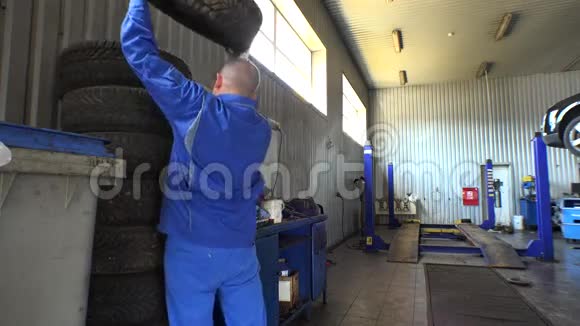 轮胎堆和男机修工一个车库换轮胎视频的预览图