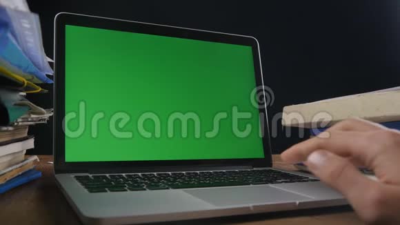 关闭人工作在笔记本电脑晚办公室与绿色屏幕在电脑前工作的商人视频的预览图