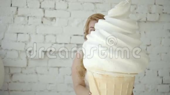 可爱的金发女郎穿着婚纱在工作室摆着巨大的冰淇淋视频的预览图