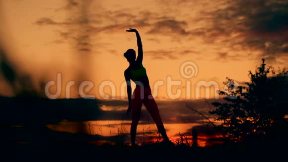 苗条的年轻女子在日落时做热身运动形状灵活运动平稳视频的预览图