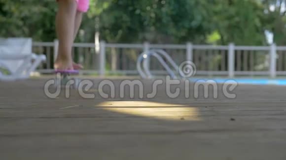一个穿着粉红色短裤的小女孩赤着脚在游泳池里滑滑板视频的预览图