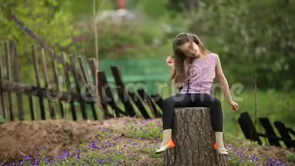 可爱的女孩坐在村屋的院子里喜欢带着耳机的音乐很开心视频的预览图