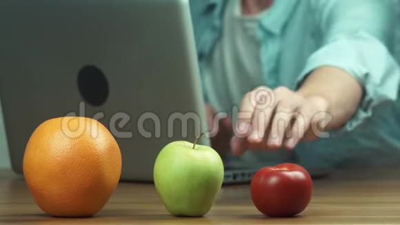 使用笔记本电脑的人面前桌子上放着橙色苹果和番茄视频的预览图