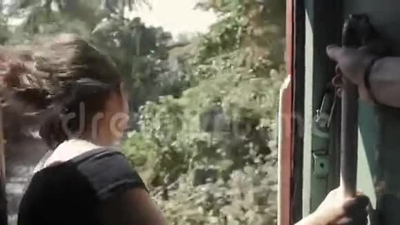 在斯里兰卡坐火车旅行的年轻女子座位没有门丛林背景视频的预览图
