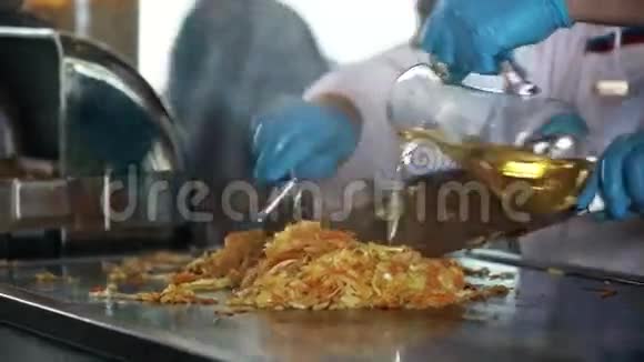 烹饪厨师用橡胶手套用两个金属铲子在炉子上准备卷心菜视频的预览图