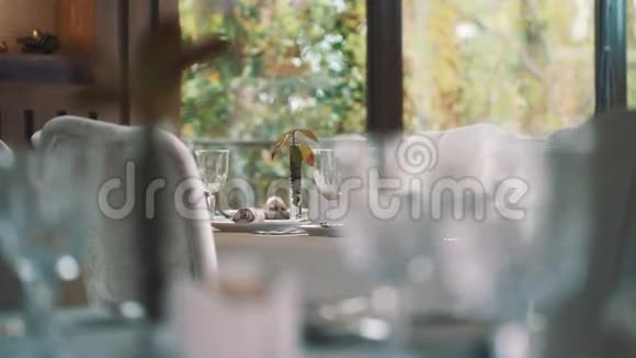 提供昂贵餐厅的餐桌服务窗户后面的树木视频的预览图