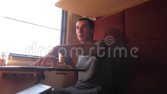 男人坐在火车车厢里捧着咖啡喝茶慢动作视频男人视频的预览图