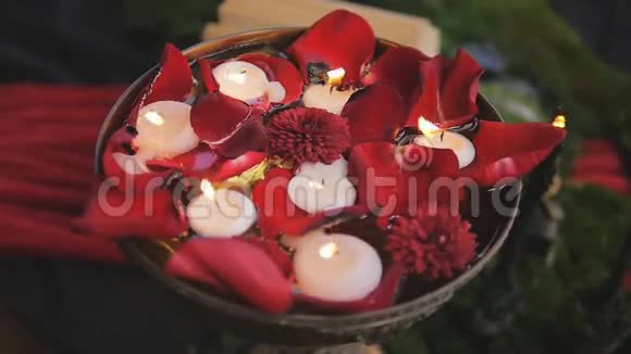 蜡烛在有玫瑰花瓣的花瓶里慢慢燃烧浪漫装饰视频的预览图