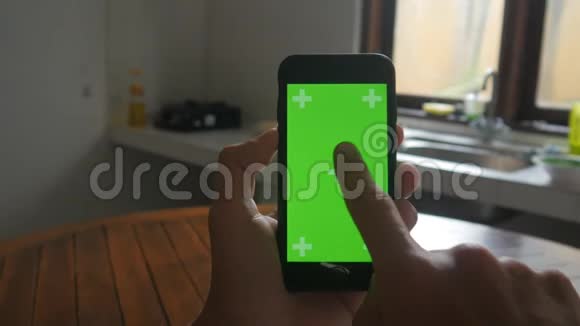 厨房中男性手触摸智能手机的特写绿色屏幕Chroma键视频的预览图
