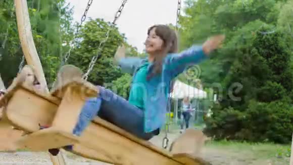 微笑的女孩在操场上玩得很开心孩子们夏天在户外玩耍在外面骑着秋千的青少年视频的预览图