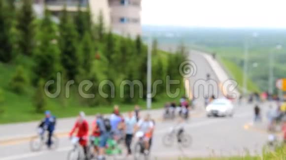 许多骑自行车的人和步行者沿着公路走山上长满了绿草和毛皮树视频的预览图