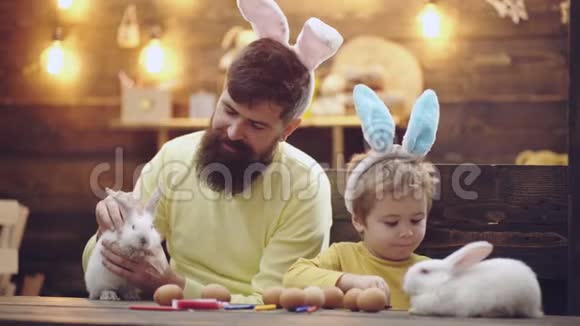 幸福的家庭正在为复活节做准备可爱的小男孩戴着兔子耳朵美丽的儿童画复活节视频的预览图