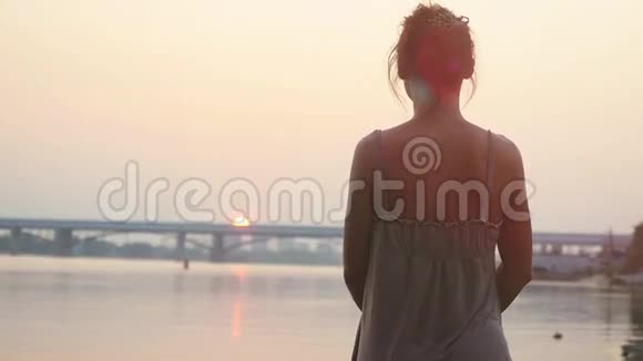 年轻的女人站在沙滩上看着太阳慢慢地下山日落时悲伤1920x1080视频的预览图