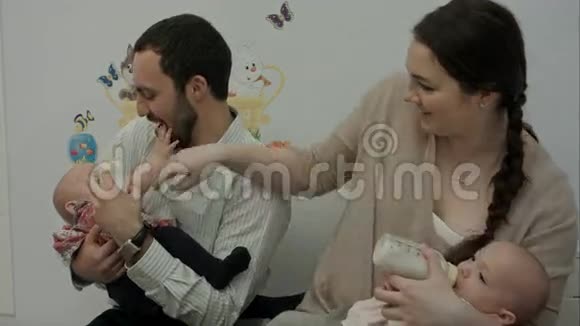 快乐的年轻父母喂养新生的双胞胎视频的预览图