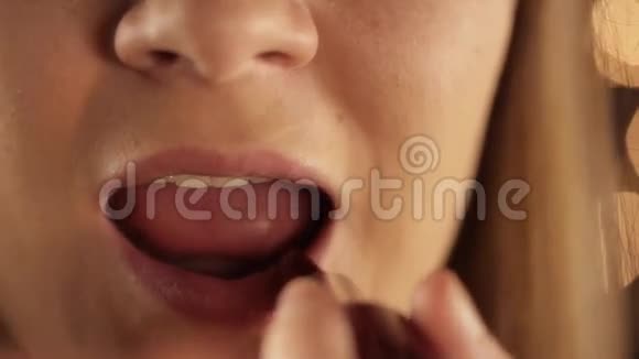 女孩把她的嘴唇涂成红色的口红特写视频的预览图