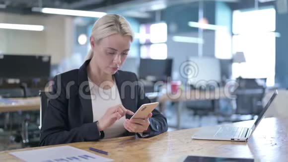 认真的女商人在工作中使用智能手机视频的预览图