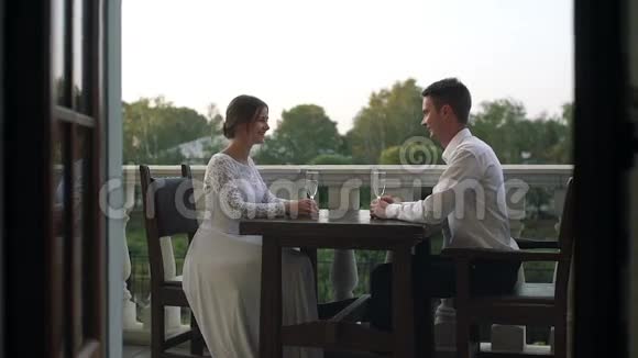 新婚之日一对美丽的恋人坐在户外餐馆的桌子旁视频的预览图