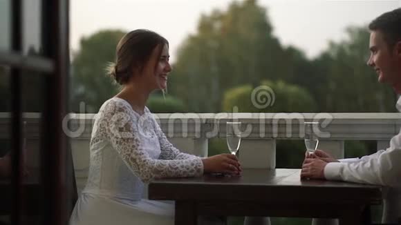 新婚之日一对美丽的恋人坐在户外餐馆的餐桌旁视频的预览图