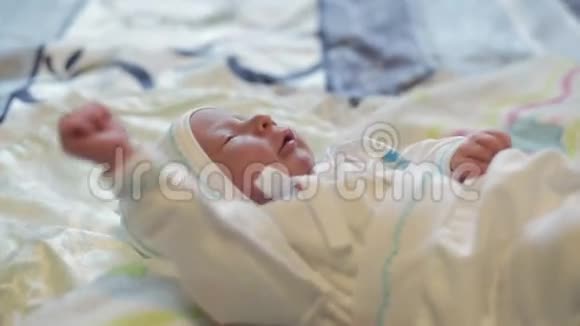 可爱的新生儿穿着白色西装躺在床上视频的预览图