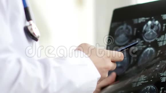 医生查看MRI扫描并给某人打短信4K超高清视频视频的预览图