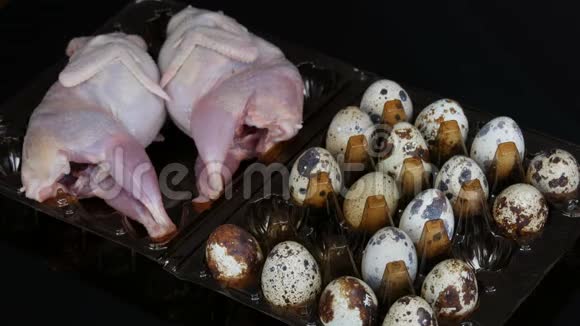 新鲜的鹌鹑肉放在一个塑料棕色托盘旁边的鹌鹑蛋黑色背景女人的手把鸡蛋放进去视频的预览图