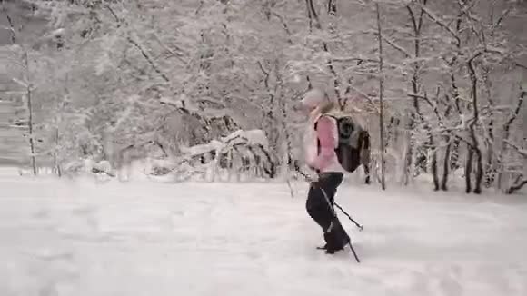 活动女性的侧景穿着温暖的白色背心和黑色裤子用滑雪杆快速行走视频的预览图