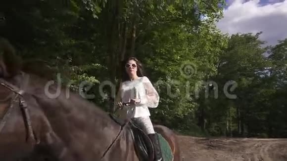 春天的时候穿白色衣服的布鲁内特在公园骑马视频的预览图