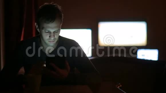 在电视屏幕背景下黑暗中看平板电脑的人视频的预览图