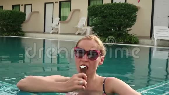 戴着太阳镜在酒店游泳池里吃冰淇淋的漂亮金发美女视频的预览图