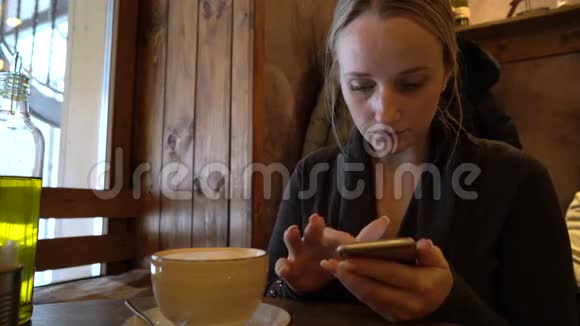 在咖啡馆里用电话的年轻女子视频的预览图