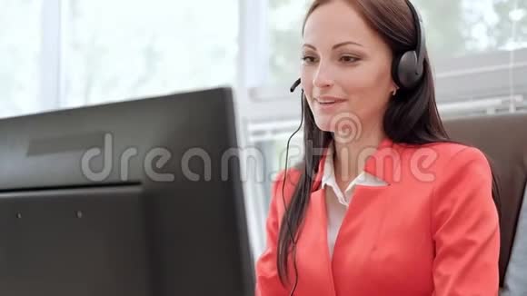 年轻迷人的女士穿着红色夹克坐在办公桌前行政首长穿着红色夹克在视频的预览图