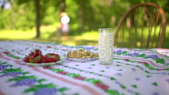 把村里的早餐收起来一杯牛奶草莓和饼干在桌子上女人和自然在闪耀视频的预览图