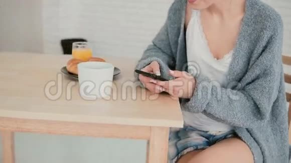 使用触摸屏近距离观看女性早餐和浏览互联网女孩在智能手机上读新书视频的预览图