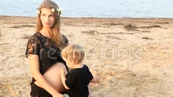 怀孕的女孩和她的儿子站在海滩上两年视频的预览图