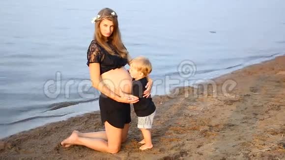怀孕的女孩和她的儿子站在海滩上两年视频的预览图