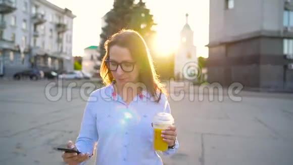 女人在智能手机上说话在街上喝果汁视频的预览图