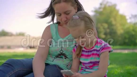 妈妈和女儿在公园里打电话玩游戏视频的预览图